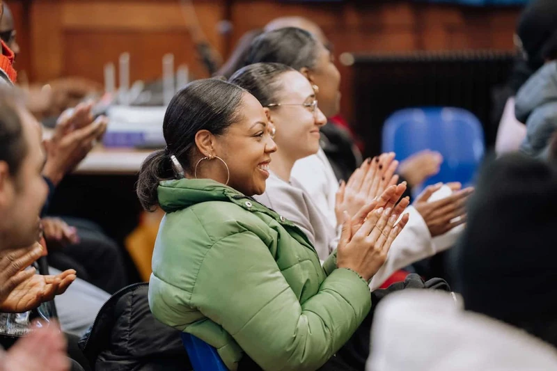 A woman laughing and clapping with friends during a Sunday gathering